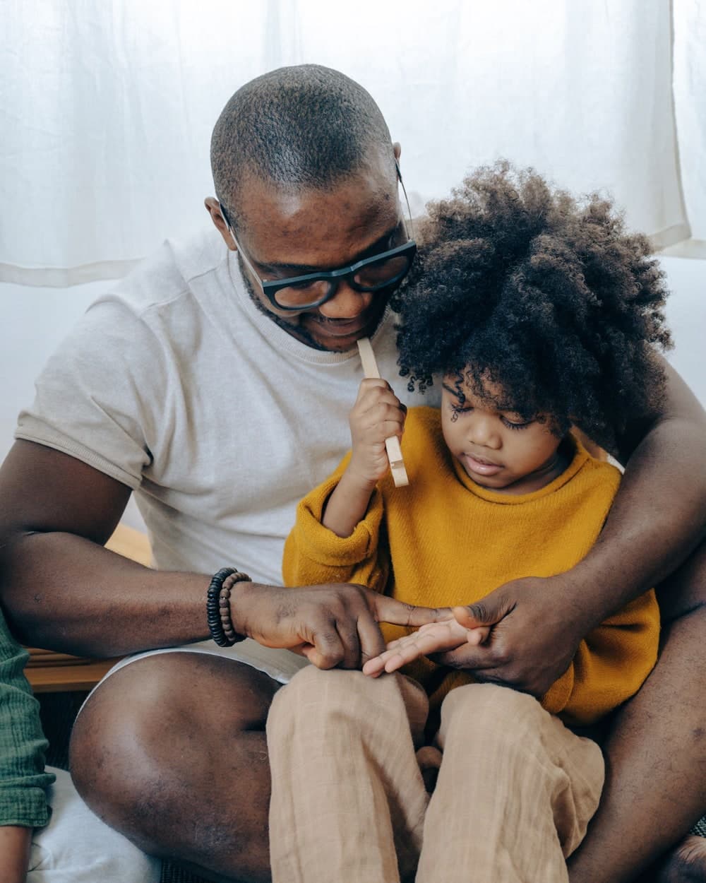 A father sitting with his young child at home, giving them his full attention