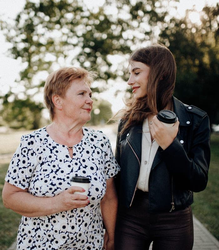 An adult daughter and her mother smiling together